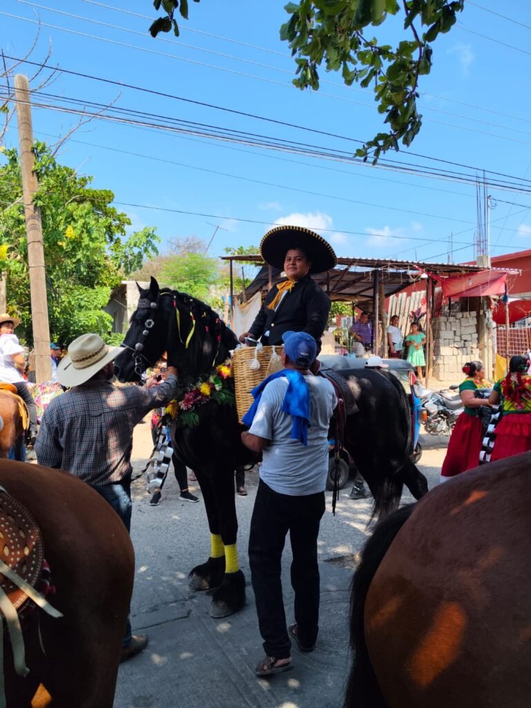 Caballos en una regada Charro con sombrero grande montando un caballo negro adornado con flores en un desfile en Juchitán.
Jinete vestido de charro a caballo con adornos florales durante una celebración oaxaqueña.
Desfile de cabalgata en Juchitán con un charro sonriente sobre un caballo negro decorado.
Celebración tradicional en Oaxaca mostrando un charro elegante a caballo con adornos florales y gente alrededor.
Fotografía de un charro montando un caballo adornado en una calle festiva de Juchitán.