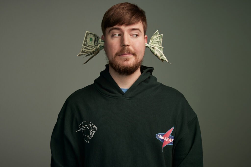 MrBeast mirando a la derecha con billetes de dólar saliendo de sus orejas.
Retrato de MrBeast con dinero en las orejas y una sudadera con su logo.
El youtuber MrBeast con un concepto visual de dinero brotando de sus orejas.
Imagen humorística de MrBeast con billetes de dólar saliendo de sus orejas.
MrBeast mostrando su peculiar estilo con dinero y suéter con logos.