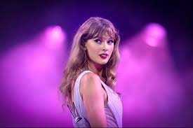 Taylor Swift mirando hacia atrás sobre el escenario iluminado con luces púrpuras.
Taylor Swift actuando en concierto bajo luces magenta y humo.
La cantante Taylor Swift en el escenario con labios rojos y vestido claro.
Imagen de Taylor Swift durante una presentación musical con iluminación púrpura.
Taylor Swift en el escenario, girando para mirar a la audiencia bajo luces de concierto.